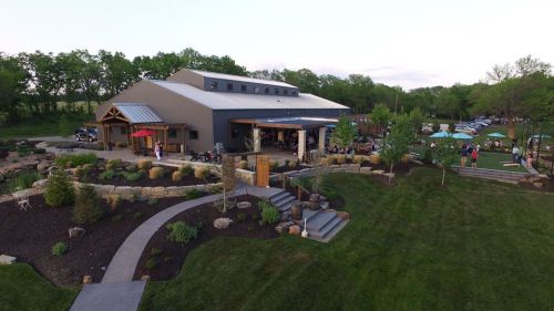 A spacious outdoor venue with a modern building, landscaped gardens, and people enjoying the surroundings.