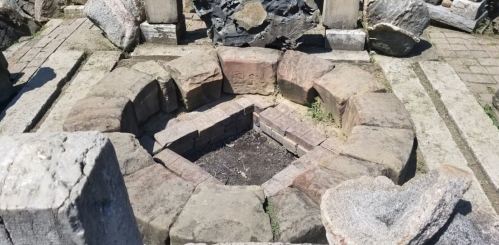 A circular stone fire pit surrounded by uneven stone blocks, with some debris scattered around.