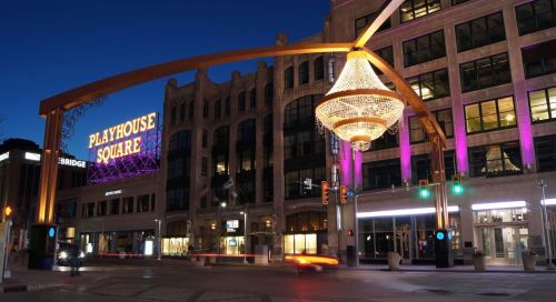 Playhouse Square sign illuminated at night, featuring a large chandelier and vibrant lights in a city setting.