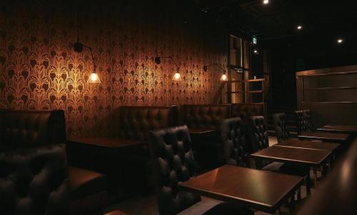 Cozy restaurant interior with dark patterned wallpaper, leather booths, and warm lighting.
