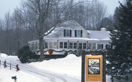 A cozy restaurant, Michael's on the Hill, surrounded by snow-covered trees and a winter landscape.