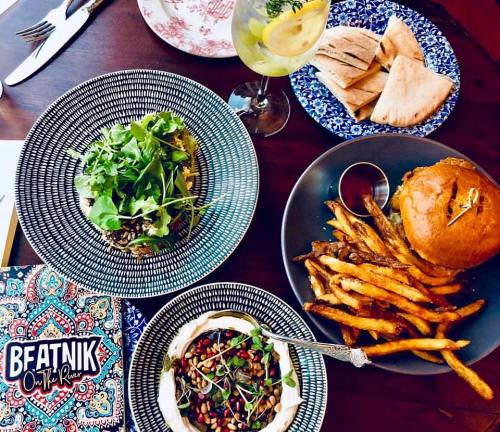 A vibrant table setting featuring a burger, fries, a salad, and a drink, with decorative plates and a menu.