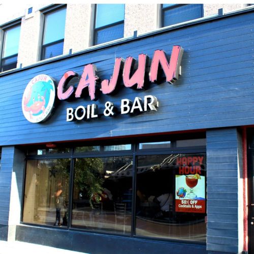 Sign for "Cajun Boil & Bar" featuring a crab logo, with a "Happy Hour" promotion visible in the window.