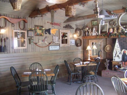 Cozy restaurant interior with wooden walls, decorative items, and empty tables set for dining.