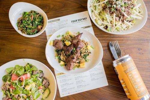 A table with four dishes: a salad, a meat bowl, a slaw, and a menu, alongside a can of beverage.