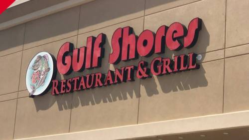 Sign for Gulf Shores Restaurant & Grill, featuring a logo with a fish and bold red lettering.
