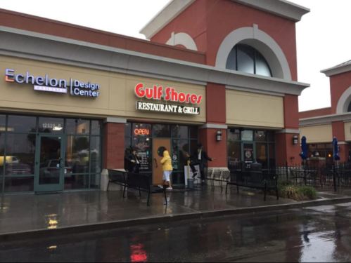 Exterior of Gulf Shores Restaurant & Grill on a rainy day, with people entering and benches outside.