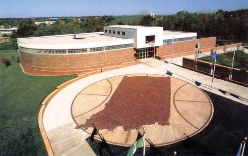 Aerial view of a modern building with a circular entrance and a large Indiana state outline in the foreground.