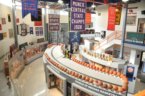 Interior view of a sports museum featuring basketballs, trophies, and banners celebrating local championships.
