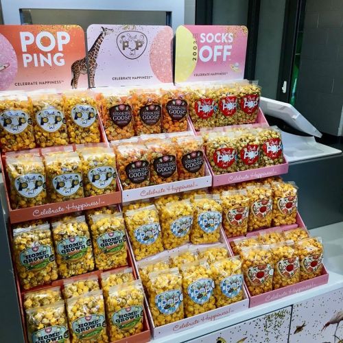 Display of colorful popcorn bags in various flavors, arranged on a stand with a cheerful theme.