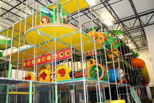 Colorful indoor play structure with slides, climbing areas, and jungle-themed decorations for children.