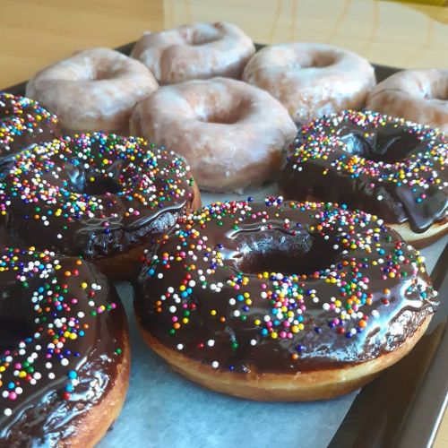 A tray of assorted donuts: some glazed and others topped with chocolate and colorful sprinkles.