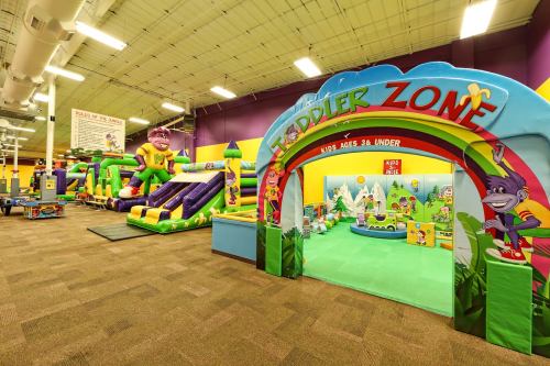 Colorful indoor play area for toddlers, featuring inflatable structures and a dedicated "Toddler Zone" entrance.