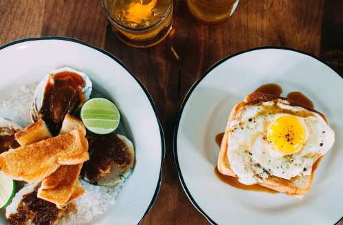Two plates of food: one with toast, lime, and sauce; the other with toast topped with a fried egg and sauce.