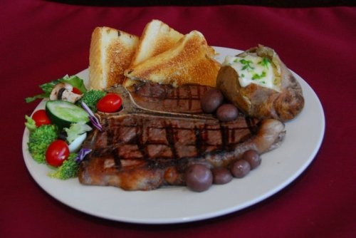 A plate featuring grilled steak, baked potato, toast, and a side of mixed vegetables and cherry tomatoes.