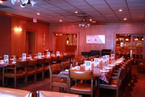 A cozy restaurant interior with wooden decor, long tables set for dining, and soft lighting.