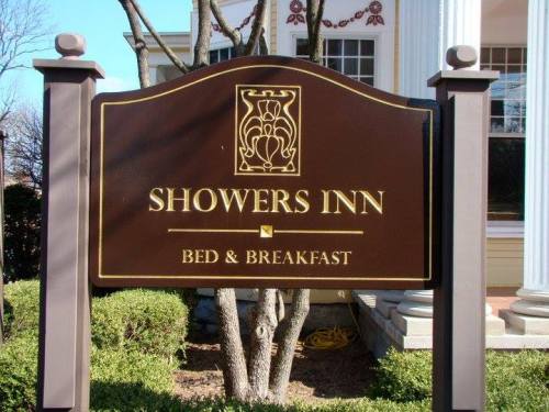 Sign for Showers Inn Bed & Breakfast, featuring a decorative design and surrounded by greenery.