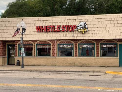 Exterior of Whistle Stop Café, featuring a sign and windows displaying "Breakfast," "Lunch," and "Restaurant."