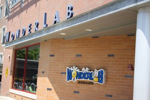 Exterior of WonderLab, a science museum, featuring a colorful sign and brick wall.