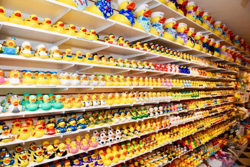 A colorful display of various rubber ducks arranged on shelves, showcasing different designs and themes.