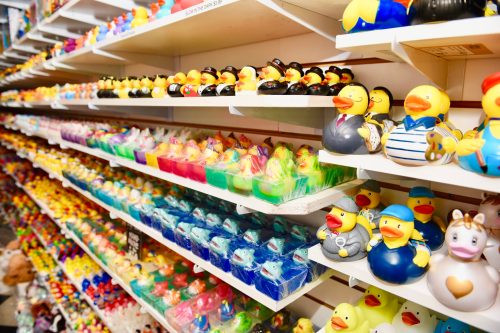 A colorful display of various rubber ducks arranged on shelves, featuring different designs and colors.
