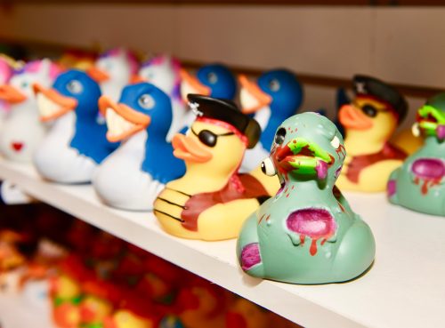 A row of colorful rubber ducks, including a pirate, a cool duck with sunglasses, and a zombie-themed duck.