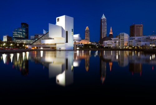 Cleveland skyline at night, featuring modern architecture and reflections in the water.