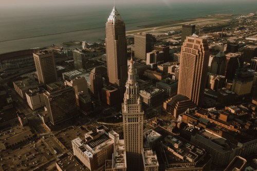 Aerial view of Cleveland's skyline featuring tall buildings and a waterfront in the background.