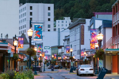 A quiet street lined with colorful banners and buildings, illuminated by street lamps in a small town.