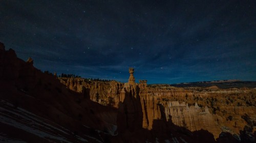 A night scene of a rock formation under a starry sky, with shadows highlighting the canyon landscape.