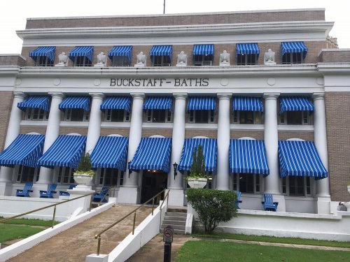Historic building with blue and white striped awnings, featuring columns and a sign that reads "Buckstaff Baths."
