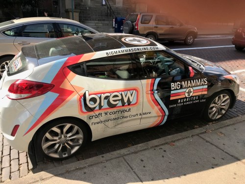 A car wrapped in advertisements for Big Mammas Burritos and Brew, featuring colorful graphics and logos.