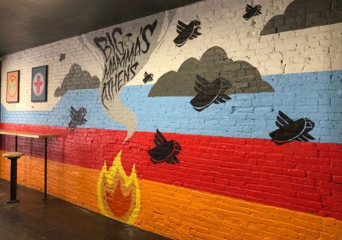 Colorful mural on a brick wall featuring birds, clouds, and flames with the text "Big Animals Atheists."
