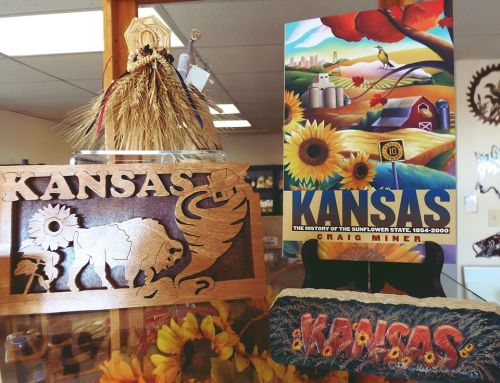 A display featuring a wooden "Kansas" sign, a book titled "Kansas" by Craig Miner, and decorative sunflowers.