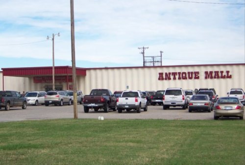 Exterior view of an antique mall with a parking lot filled with cars and a clear blue sky in the background.