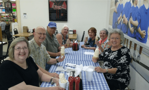 A group of six people enjoying ice cream at a table with a checkered tablecloth in a casual setting.