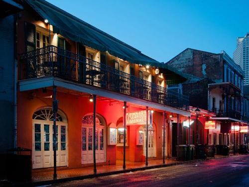 A colorful seafood market illuminated at dusk, with balconies and a vibrant atmosphere in a New Orleans street.