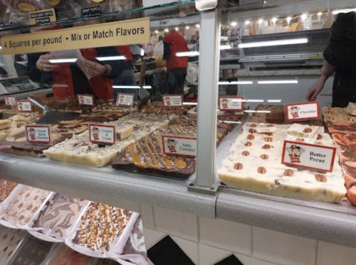 A display case filled with various types of fudge and chocolate treats, labeled with flavor names.