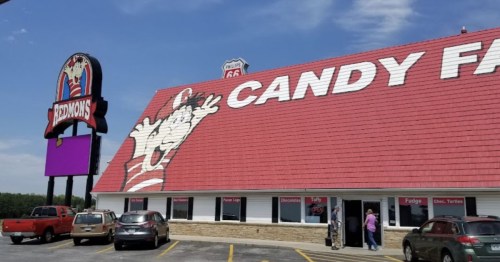 A large candy store with a red roof and a cartoon character on the side, featuring a sign for Route 66.