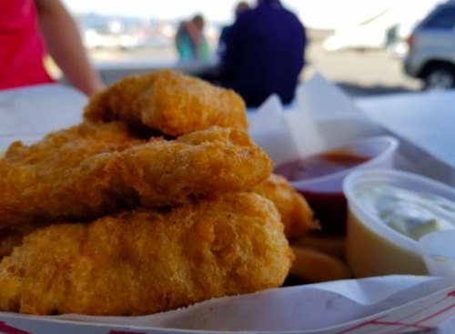 A close-up of golden fried chicken tenders served with dipping sauces on a tray.