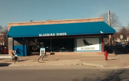 Exterior of Bluebird Diner featuring a blue awning and a large window with a bird logo.