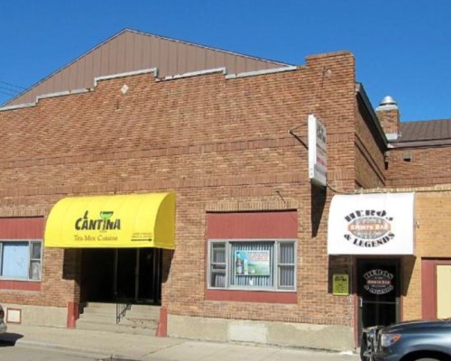 A brick building featuring a yellow awning for a restaurant and a sign for a bar named "Huro's Legends."