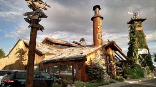 A rustic wooden building with a chimney labeled "BBQ," surrounded by trees and a cloudy sky.