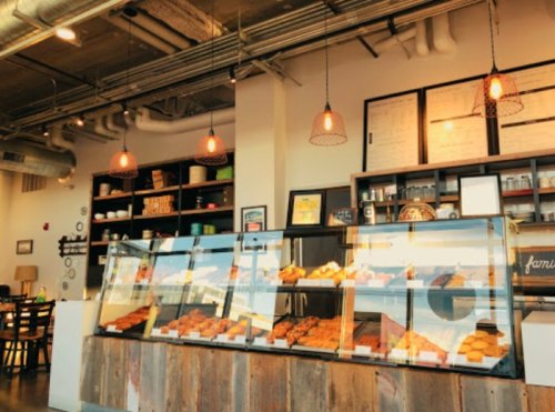 A cozy café interior featuring a display case filled with pastries and warm lighting.