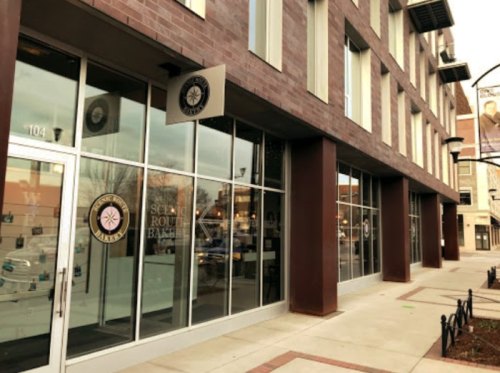 Exterior view of a modern building with large glass windows and a sign for "Science Route Bakery."