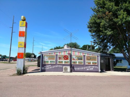 A colorful diner with a retro sign, featuring menu boards and a clear blue sky in the background.