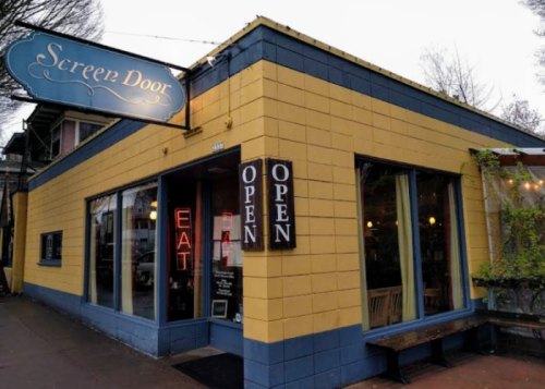 A yellow and blue restaurant exterior with a sign reading "Screen Door" and an "Open" sign in the window.
