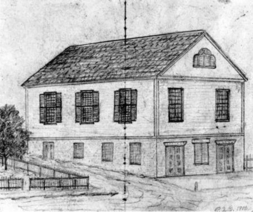 Sketch of a two-story building with shutters, a gabled roof, and a fenced yard, dated 1910.