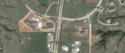 Aerial view of a highway intersection with nearby businesses, including a hotel and a car wash.