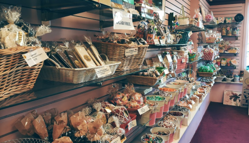 A colorful display of various candies and treats in baskets and bowls on shelves in a sweet shop.